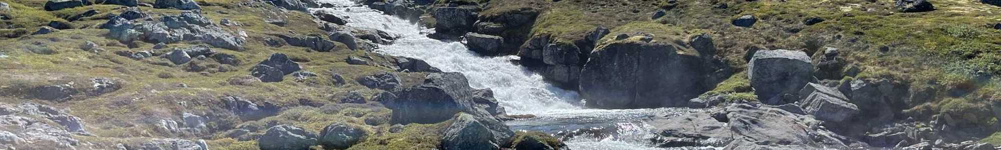 Mountain stream flowing over rocks with snow-covered peaks in the background